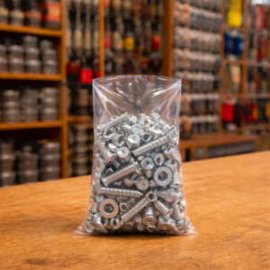 Bolsa de plástico transparente de polietileno con tornillos y tuercas en interior, ideal para ferretería y almacenamiento industrial.